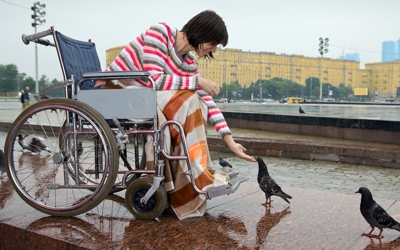 девушка на коляске кормит голубей